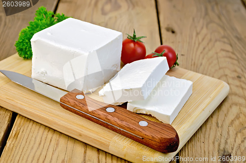 Image of Feta cheese on the board with tomatoes and parsley
