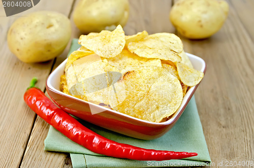 Image of Chips in a bowl with hot peppers and potatoes on board