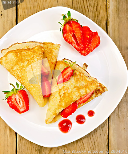 Image of Pancakes with strawberries and jam on plate and board