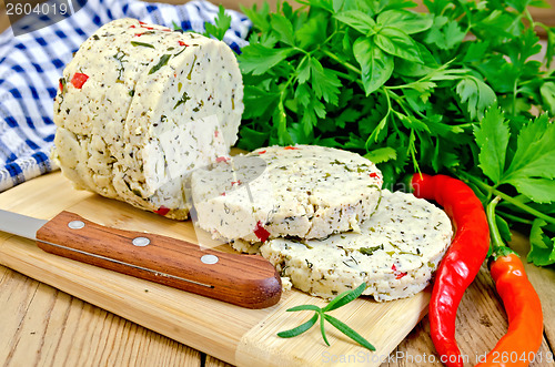 Image of Cheese homemade with hot peppers on board with knife