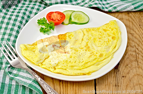 Image of Omelet with vegetables and fork on a board