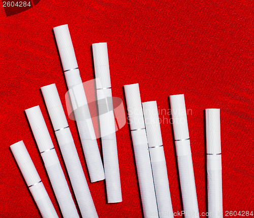 Image of scattered white cigarettes on red background