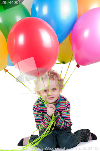 Image of Little girl with multicolored air balloons sitting