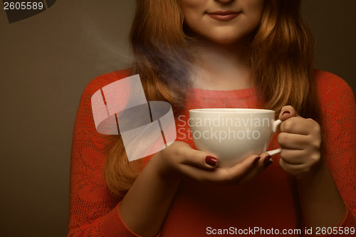 Image of woman holding hot cup and smiles