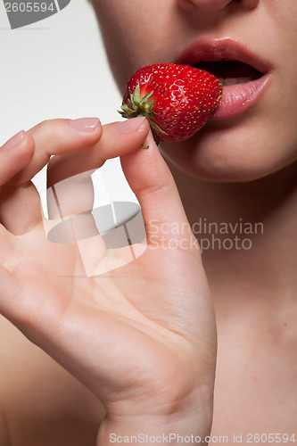 Image of Young woman biting strawberry isolated on white