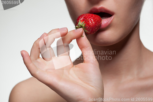 Image of Young woman biting strawberry isolated on white