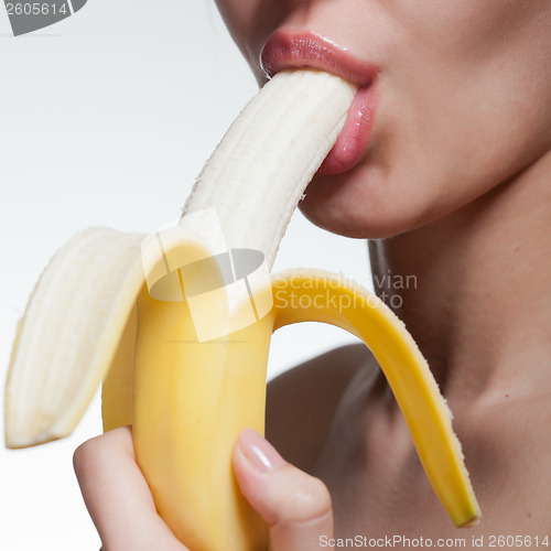 Image of Young woman biting banana isolated on white