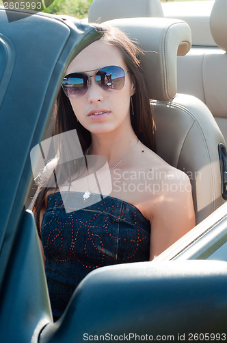 Image of Woman in sunglasses sitting in cabrio