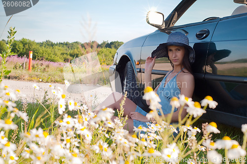 Image of Beautiful brunette woman sitting near car