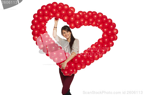 Image of Smiling woman holding red balloon heart