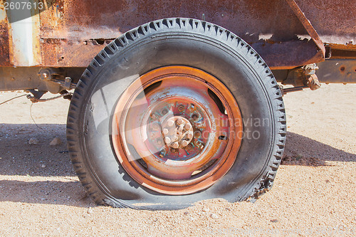 Image of Detail of a vintage abandoned flat car tire on the side of a roa