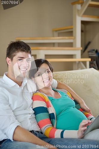 Image of pregnant couple at home using tablet computer