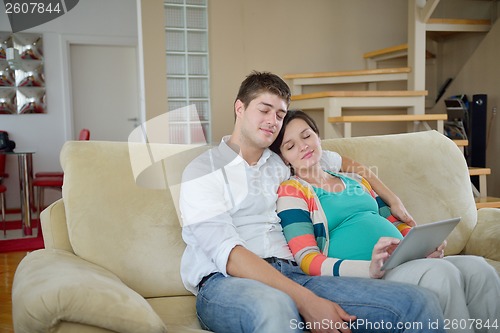 Image of pregnant couple at home using tablet computer