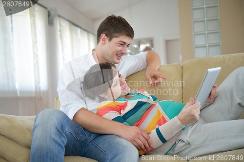 Image of pregnant couple at home using tablet computer