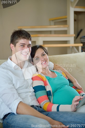 Image of pregnant couple at home using tablet computer