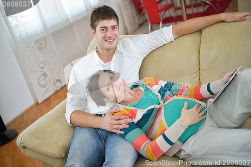 Image of pregnant couple at home using tablet computer