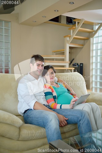 Image of pregnant couple at home using tablet computer