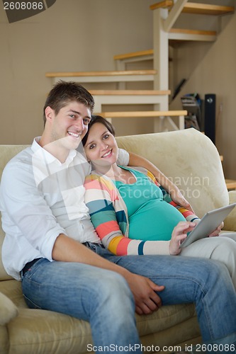 Image of pregnant couple at home using tablet computer