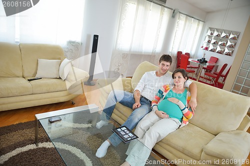 Image of pregnant couple at home using tablet computer