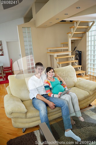 Image of pregnant couple at home using tablet computer