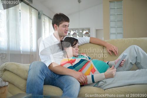 Image of pregnant couple at home using tablet computer