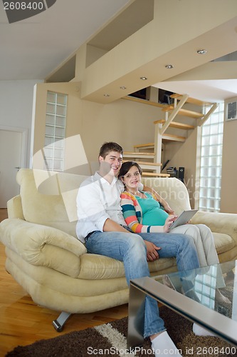 Image of pregnant couple at home using tablet computer