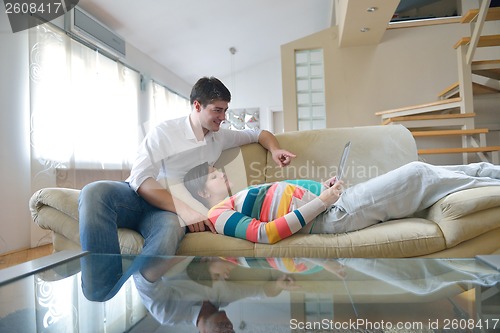Image of pregnant couple at home using tablet computer