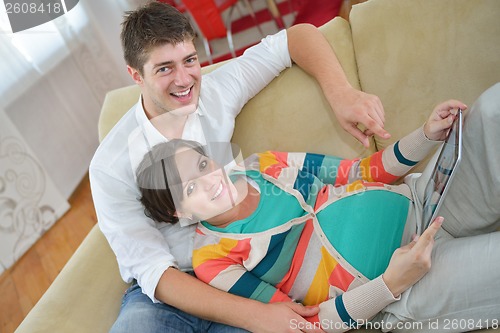 Image of pregnant couple at home using tablet computer