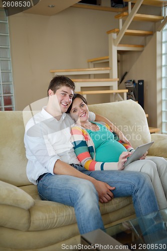 Image of pregnant couple at home using tablet computer
