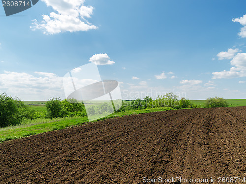 Image of black plowed field and blue sky with clouds