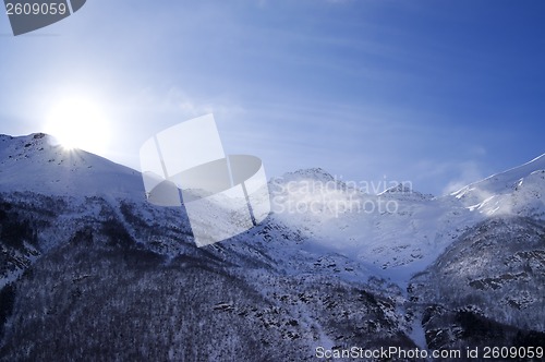 Image of Snowy mountains in haze and sky with sun, view from off piste sl