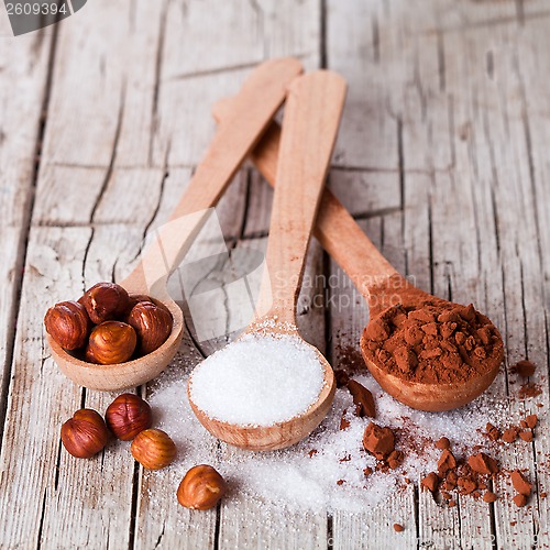 Image of sugar, hazelnuts and cocoa powder in spoons 