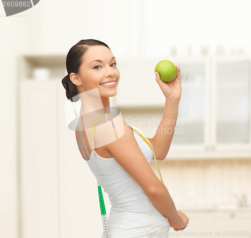 Image of sporty woman with apple and measuring tape