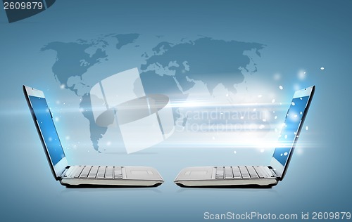 Image of two laptop computers with world map hologram