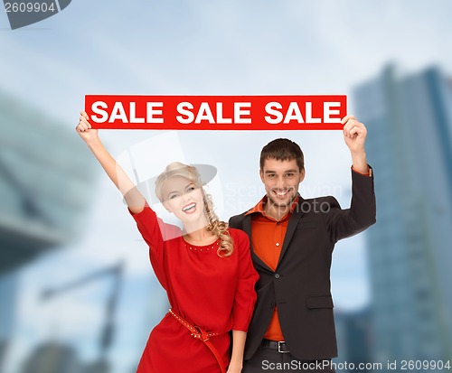 Image of smiling woman and man with red sale sign