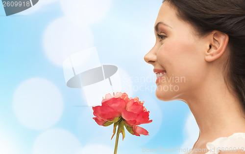 Image of smiling woman smelling flower