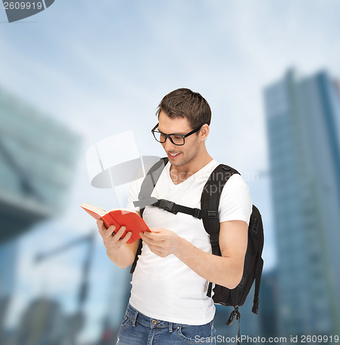 Image of student in eyeglasses with backpack and book