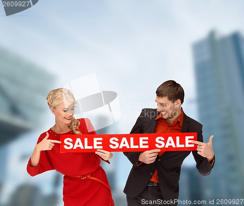 Image of smiling woman and man with red sale sign