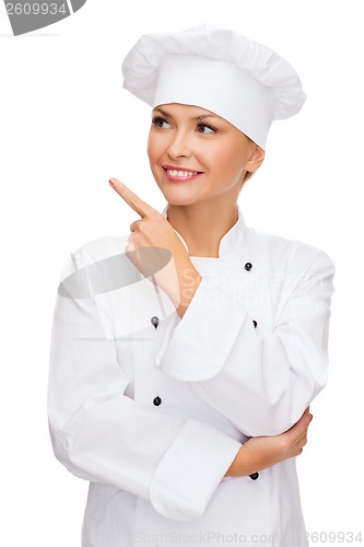 Image of smiling female chef pointing finger to sonething