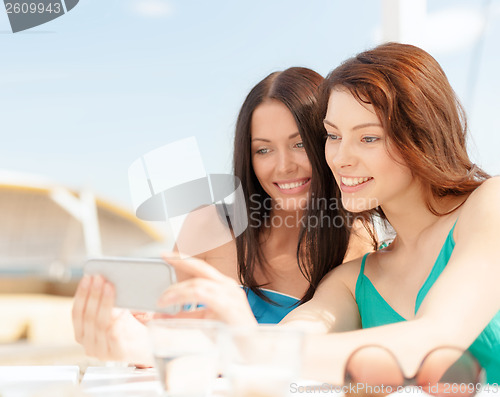 Image of girls looking at smartphone in cafe on the beach