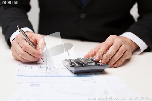 Image of close up of businessman with papers and calculator