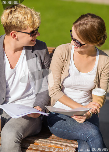 Image of two students with books, notebooks and folders