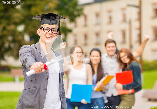 Image of smiling teenage boy in corner-cap with diploma