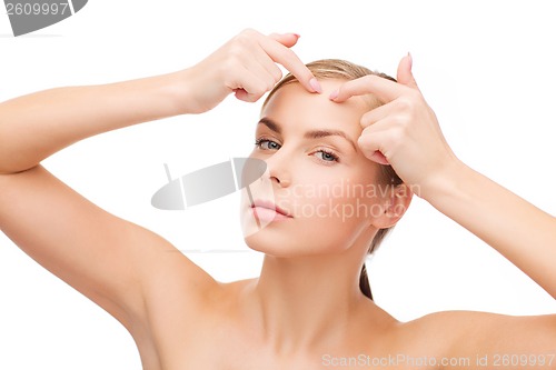 Image of young woman squeezing acne spots