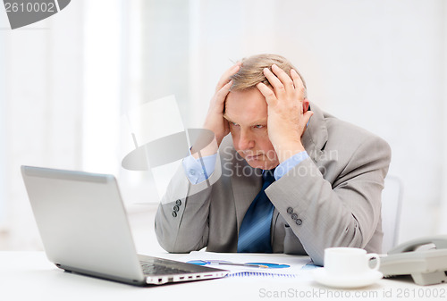 Image of upset older businessman with laptop and telephone