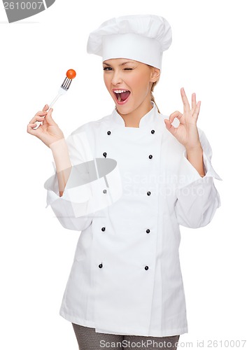 Image of smiling female chef with fork and tomato