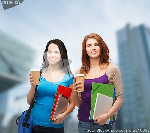 Image of two students with bag, folders, tablet and coffee