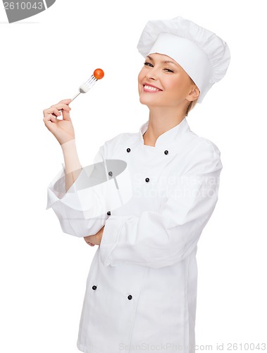 Image of smiling female chef with fork and tomato