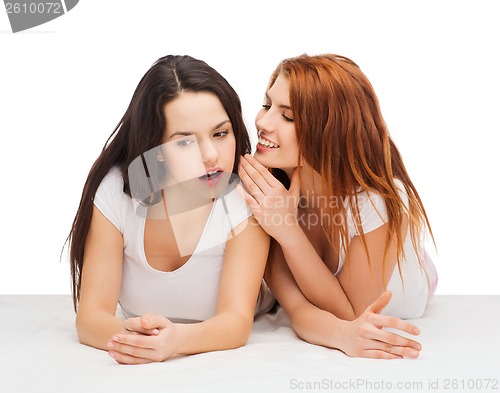 Image of two smiling girls whispering gossip