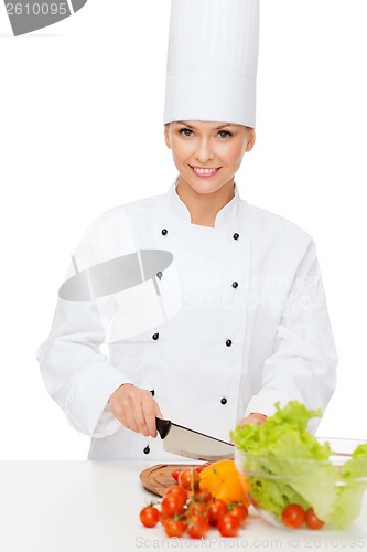 Image of smiling female chef chopping vagetables